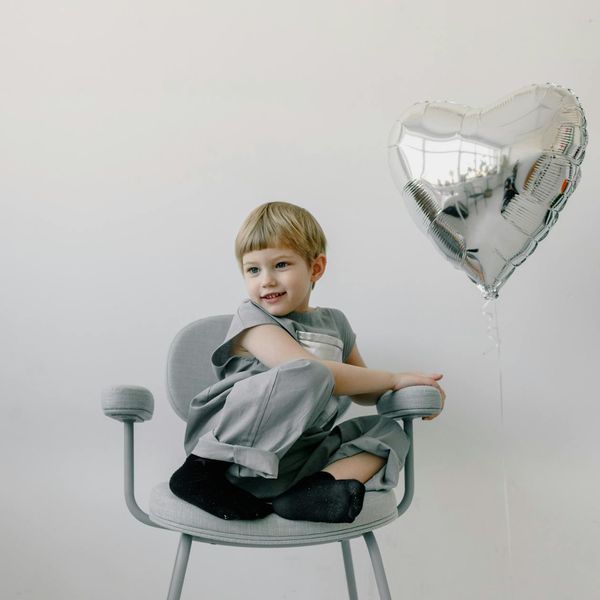 Happy child in a playful yoga pose on a silver background.