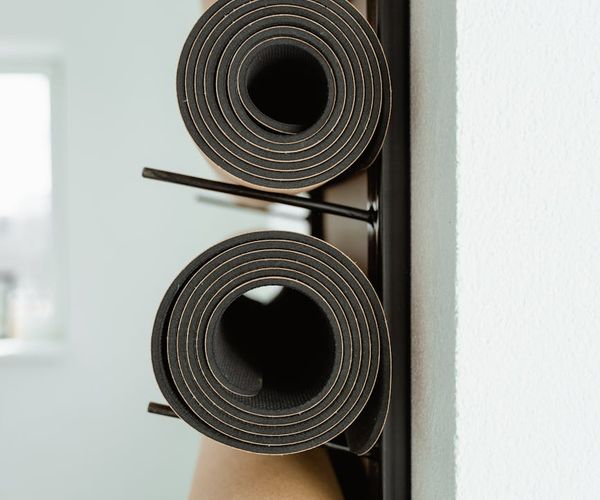 Yoga mats rolled up in a clean studio with silver light.